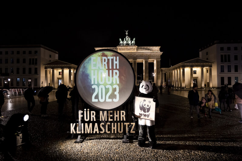 Der WWF Panda steht vor dem Brandenburgertor. Auf einem Transparent steht "für mehr Klimaschutz"